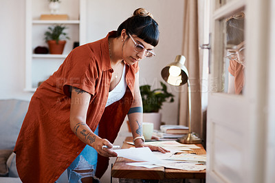 Buy stock photo Shot of a an artist looking at her sketches on a desk at home