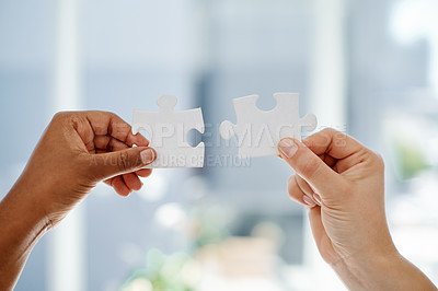 Buy stock photo Cropped shot of two unrecognizable businesswomen holding puzzle pieces inside an office