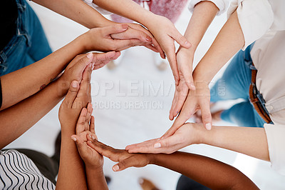 Buy stock photo Low angel shot of a group of unrecognizable businesspeople joining hands in circular formation inside an office
