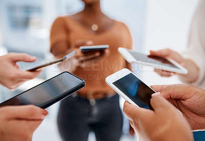 Buy stock photo Cropped shot of an unrecognizable group of businesswomen using their smartphones inside an office
