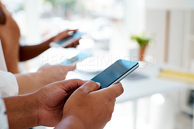 Buy stock photo Cropped shot of an unrecognizable group of businesswomen using their smartphones inside an office