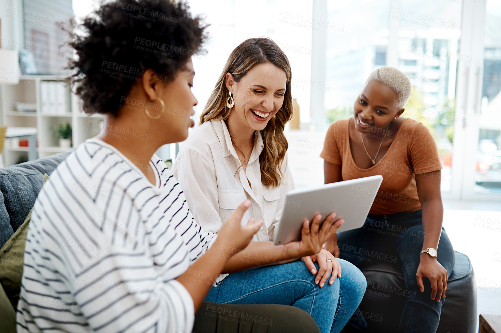 Buy stock photo Shot of a group of businesswomen working together on a digital tablet in an office
