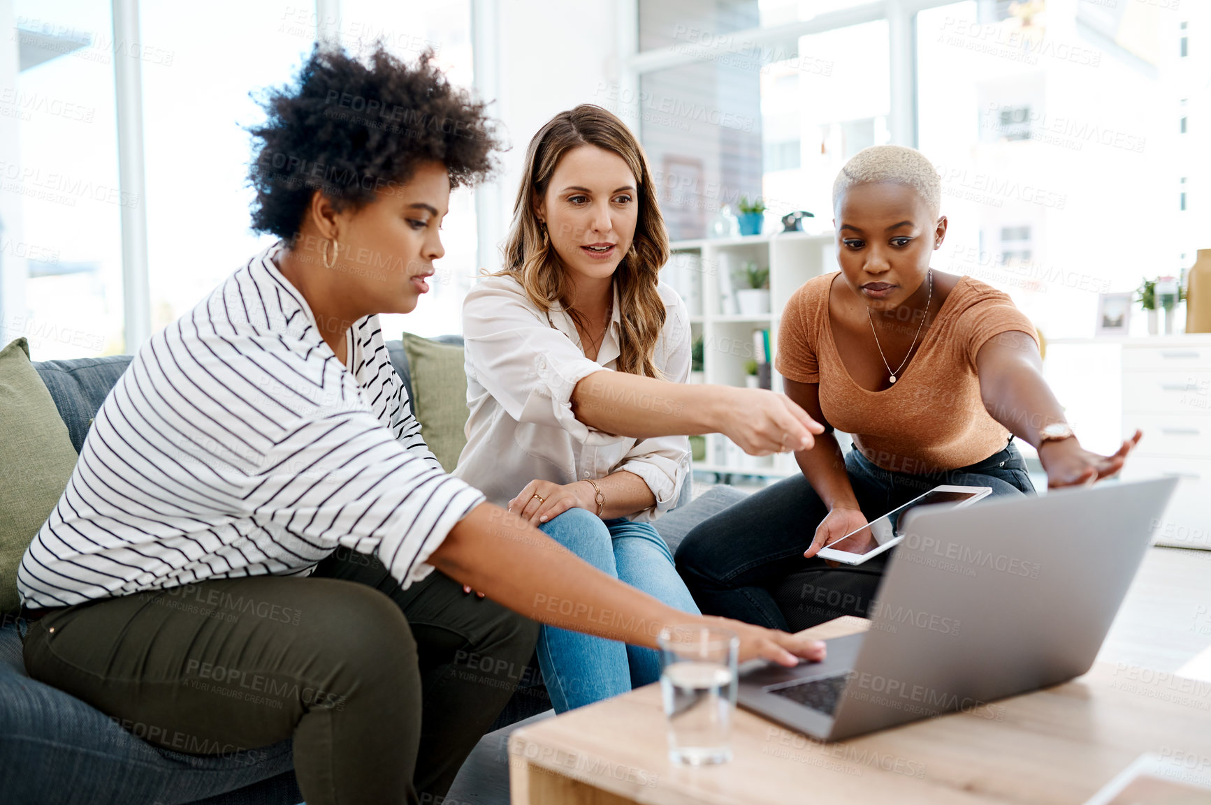 Buy stock photo Shot of a group of businesswomen working together on a laptop in an office