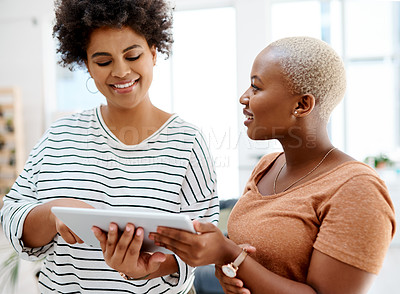 Buy stock photo Shot of two businesswomen working together on a digital tablet in an office