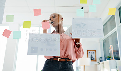 Buy stock photo Shot of a young businesswoman using a digital tablet while brainstorming with notes on a glass wall in an office