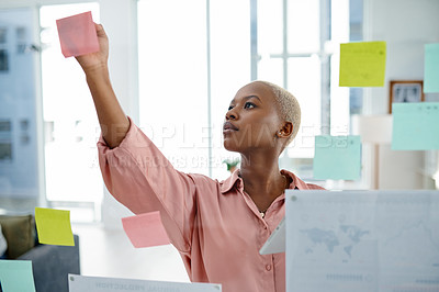 Buy stock photo Shot of a young businesswoman brainstorming with notes on a glass wall in an office