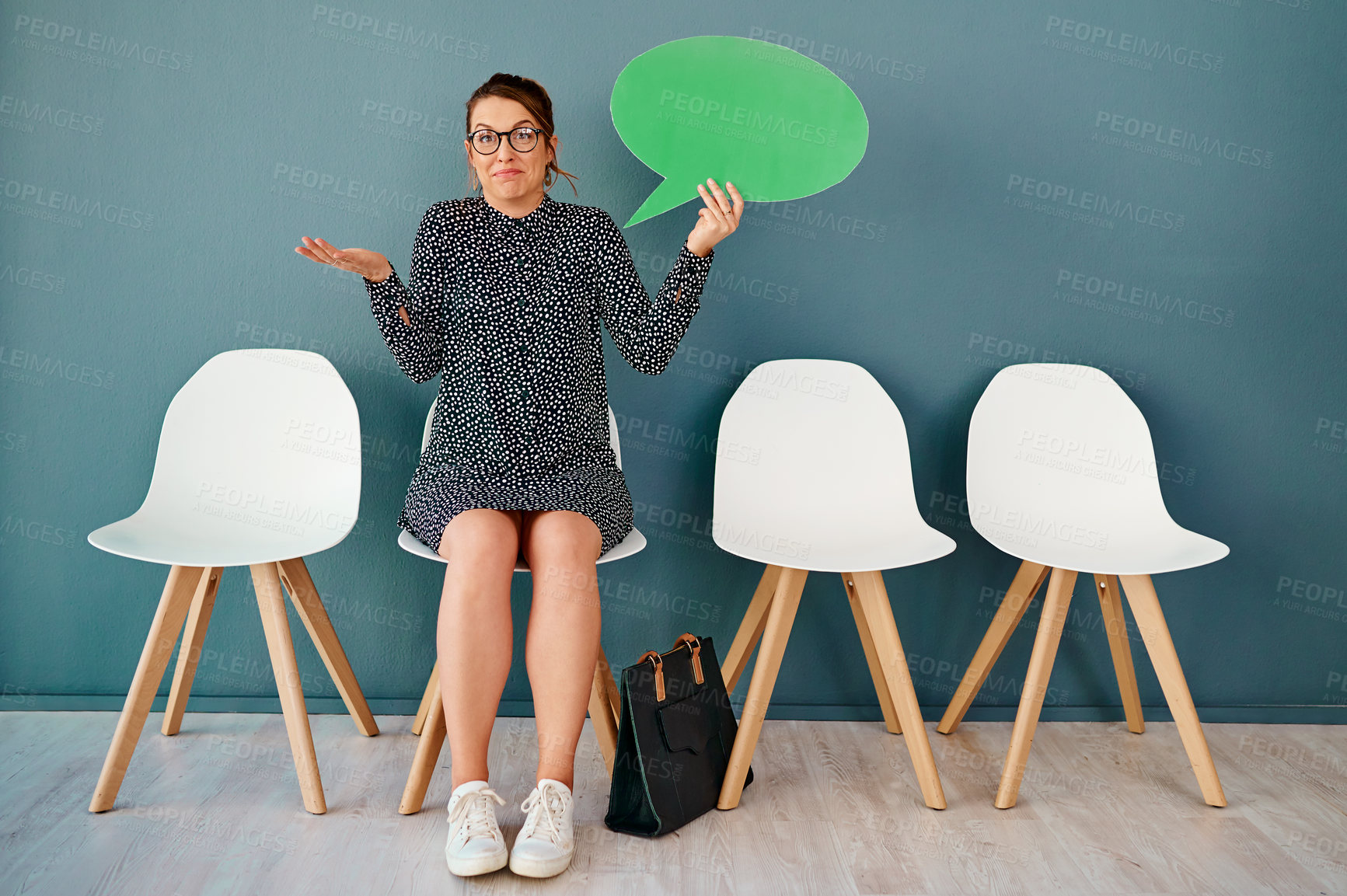 Buy stock photo Studio portrait of an attractive young businesswoman holding up a speech bubble while sitting in line against a grey background