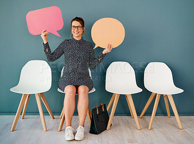 Buy stock photo Studio portrait of an attractive young businesswoman holding up speech bubbles while sitting in line against a grey background