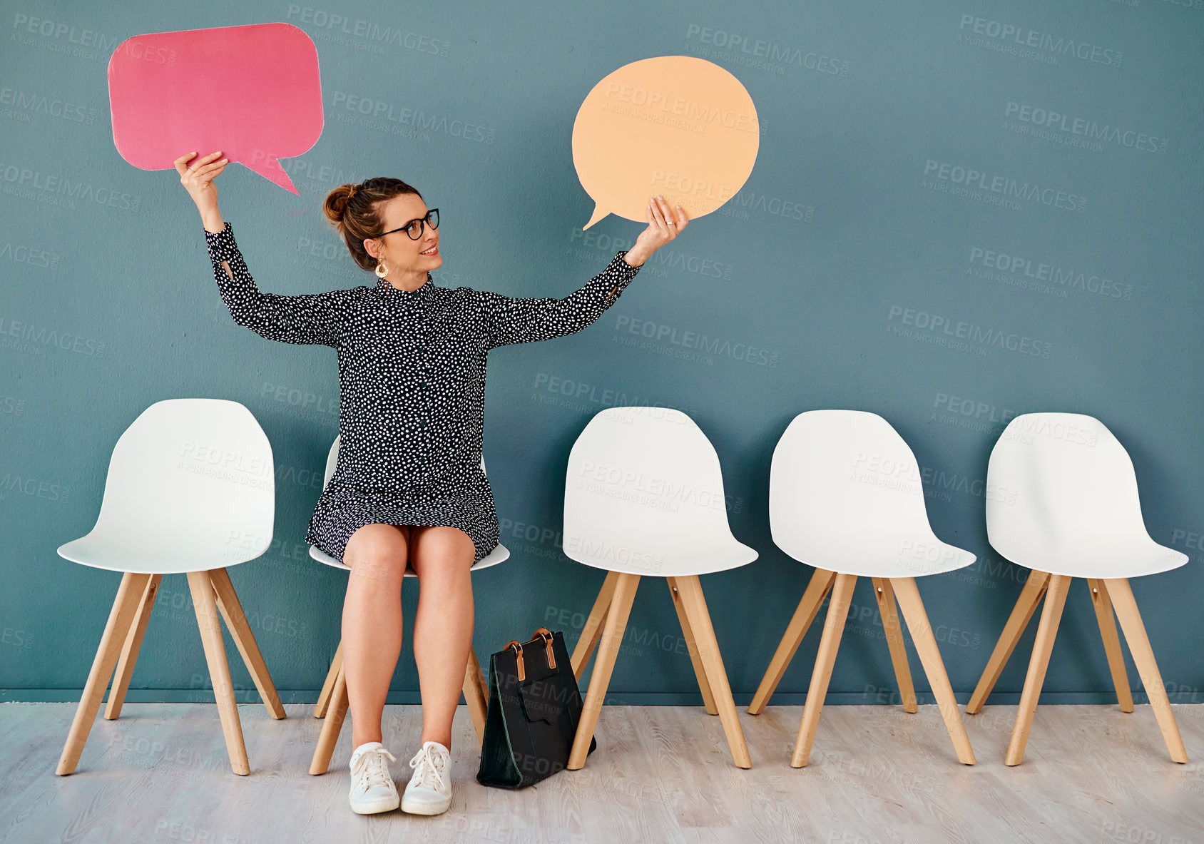 Buy stock photo Studio shot of an attractive young businesswoman holding up speech bubbles while sitting in line against a grey background