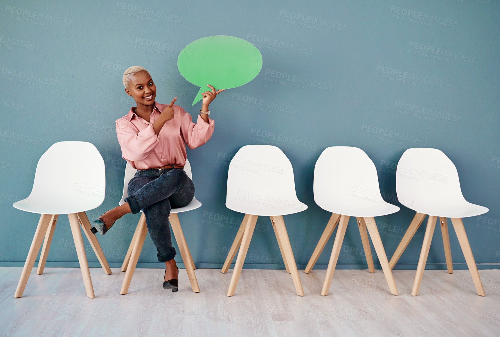 Buy stock photo Studio portrait of an attractive young businesswoman pointing to a speech bubble while siting in line against a grey background
