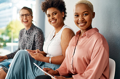 Buy stock photo Cropped portrait of a group of attractive young businesswomen using wireless technology while sitting in line in a modern office