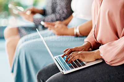 Buy stock photo Cropped shot of a group of unrecognizable businesswomen using wireless technology while sitting in line in a modern office