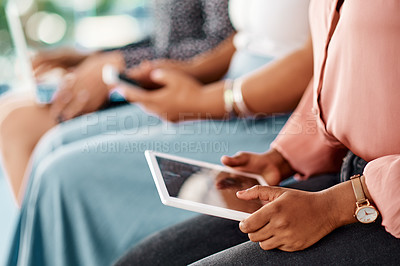 Buy stock photo Cropped shot of a group of unrecognizable businesswomen using wireless technology while sitting in line in a modern office