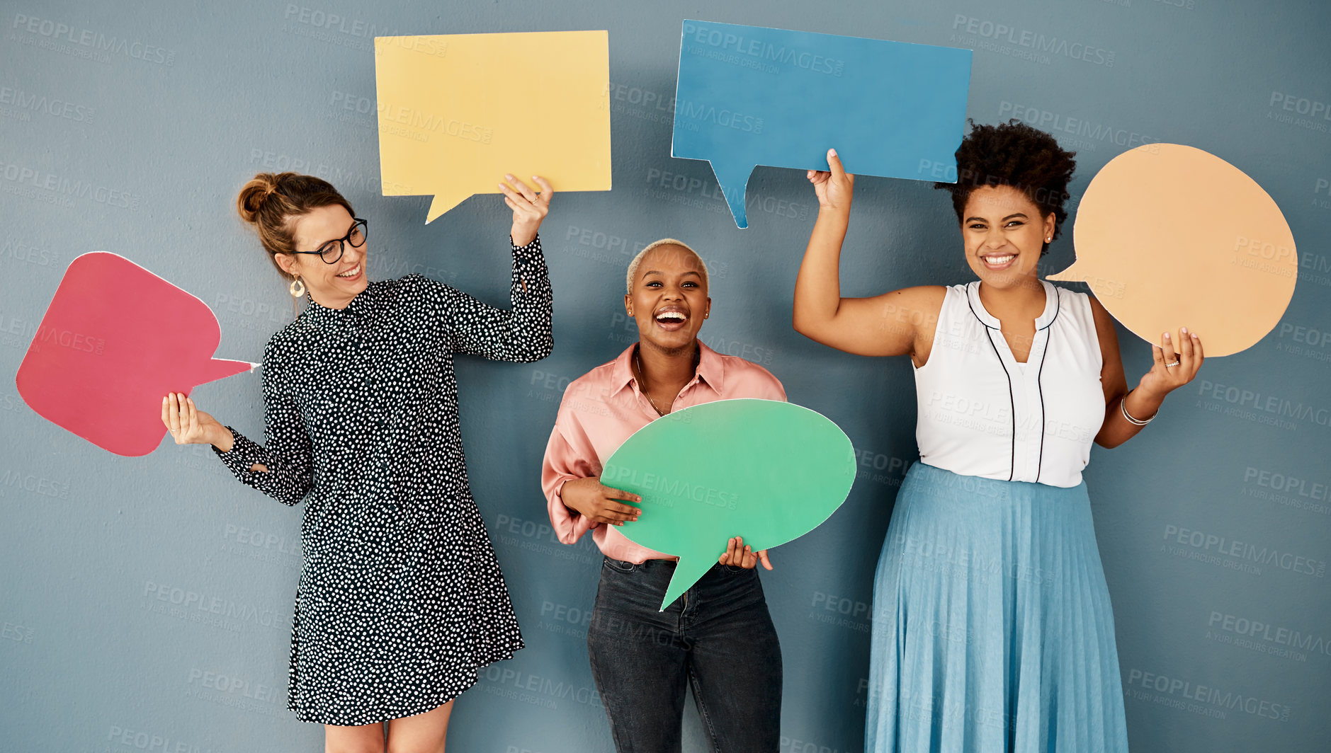 Buy stock photo Studio shot of a group of attractive young businesswomen holding speech bubbles while standing against a grey background