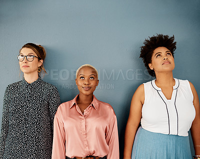 Buy stock photo Studio shot of a group of three attractive young businesswomen looking thoughtful while standing against a grey background