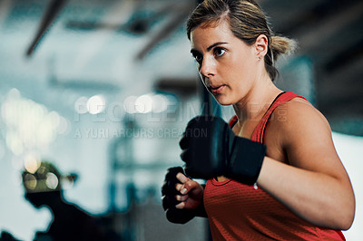 Buy stock photo Cropped shot of an attractive young female kickboxer working out in the gym