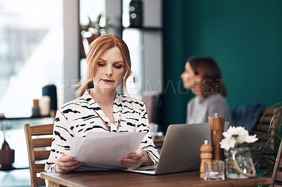 Buy stock photo Cropped shot of an attractive middle aged woman doing paperwork while being seated inside of a coffee shop during the day