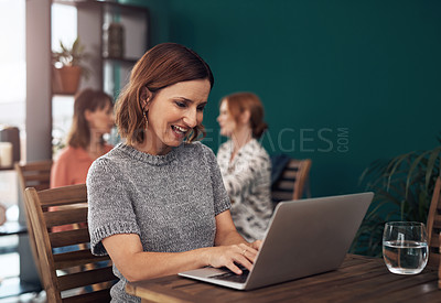 Buy stock photo Cropped shot of an attractive middle aged woman working on her laptop while being seated inside of a coffee shop during the day
