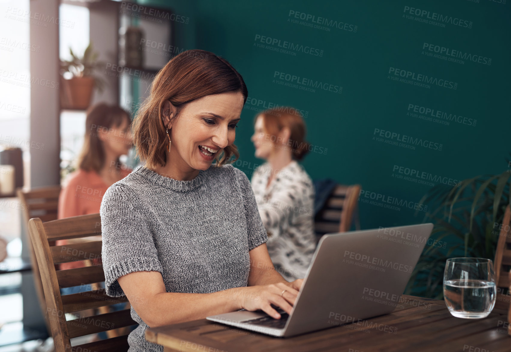 Buy stock photo Cropped shot of an attractive middle aged woman working on her laptop while being seated inside of a coffee shop during the day