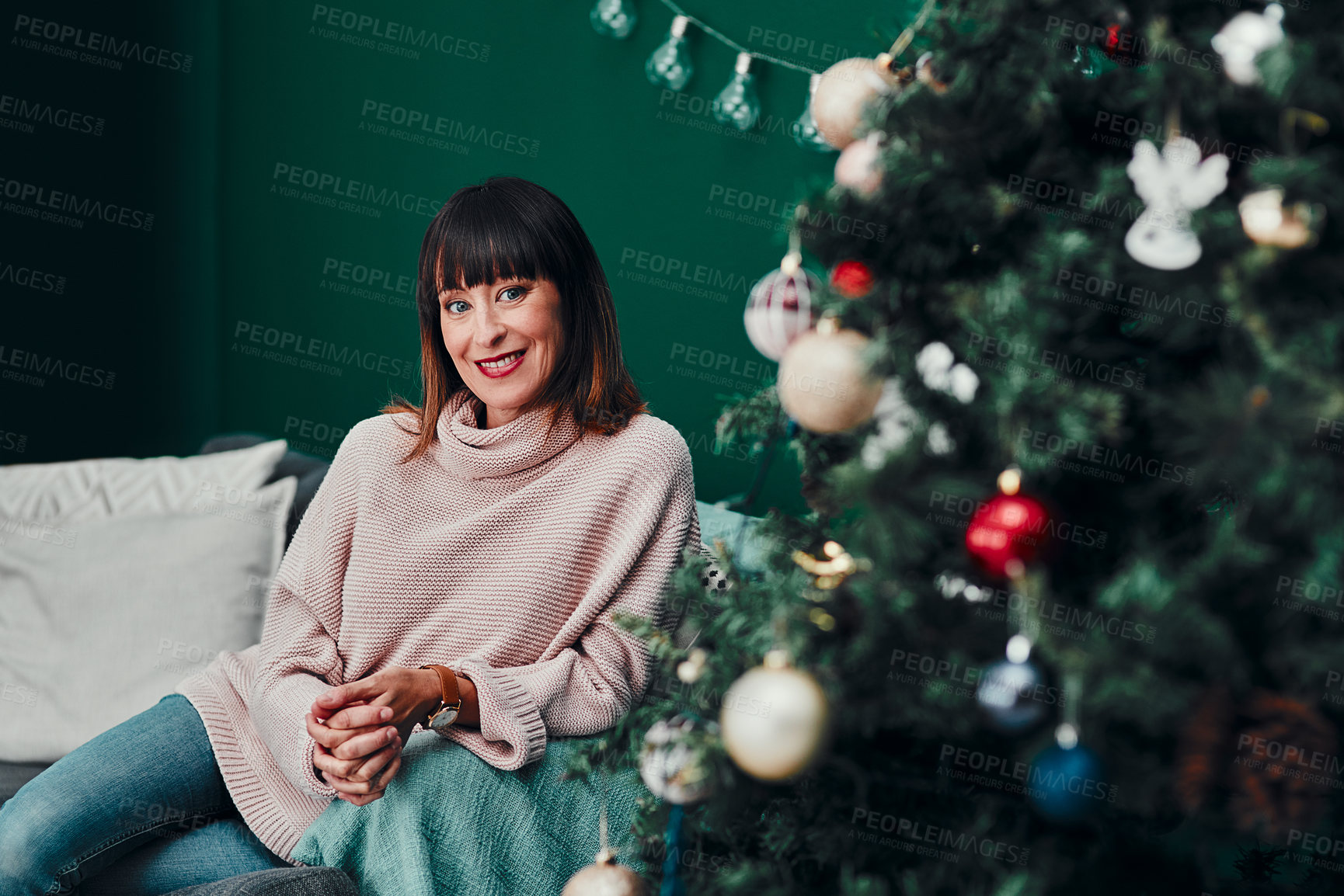 Buy stock photo Christmas, portrait and woman on sofa by tree for interior, decoration and season happiness in living room. Festive, holiday and person on couch for relaxation, celebration and tradition in winter