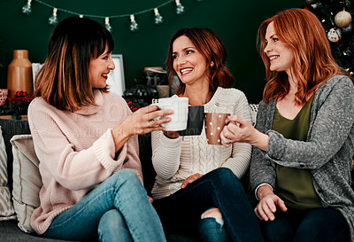 Buy stock photo Cropped shot of three attractive middle aged women seated on a sofa together while drinking coffee at home during Christmas time