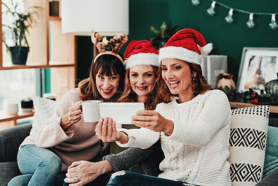 Buy stock photo Cropped shot of three attractive middle aged women taking self portraits together with a cellphone at home during Christmas time