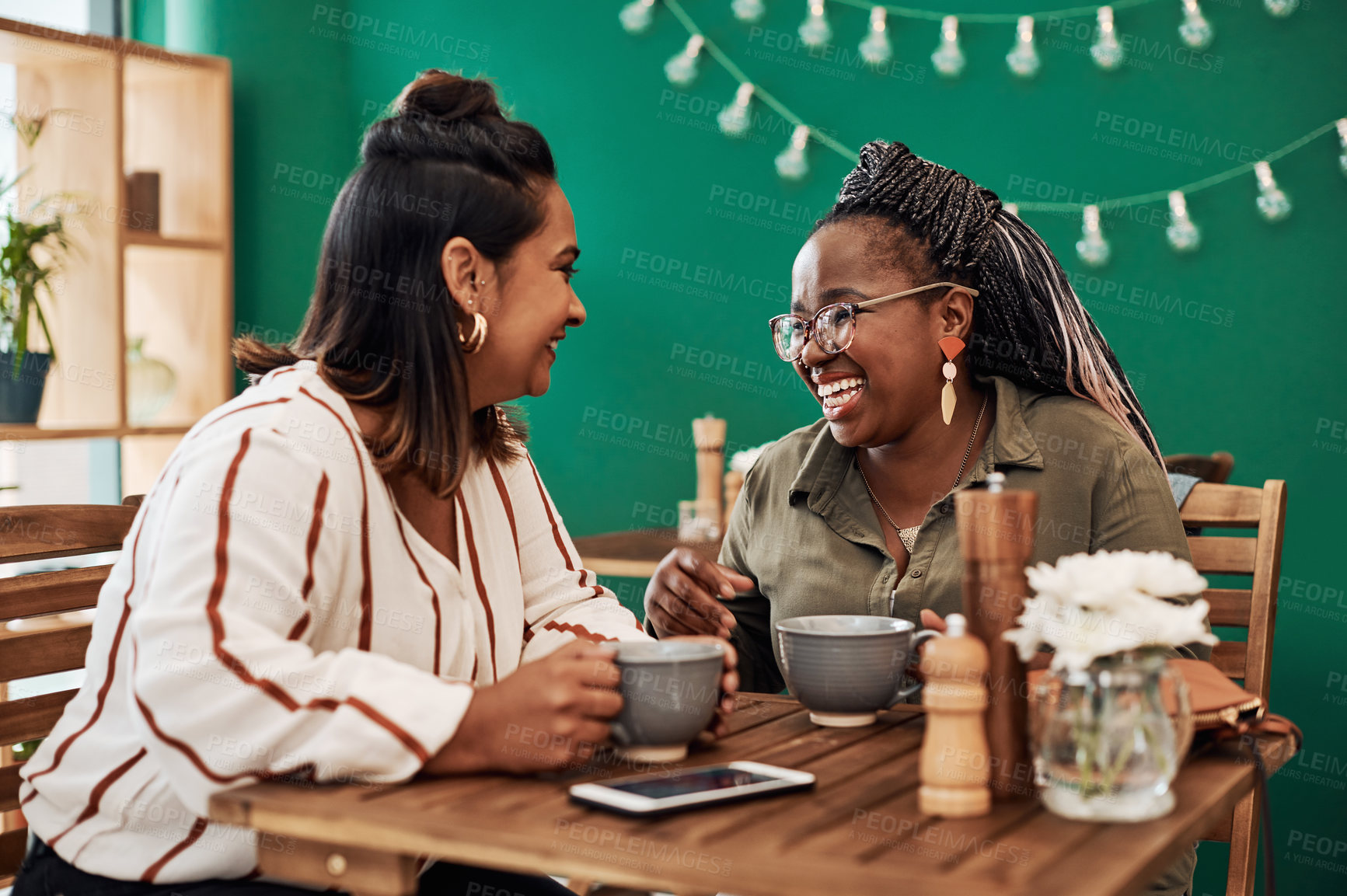 Buy stock photo Shot of two young women chatting at a cafe