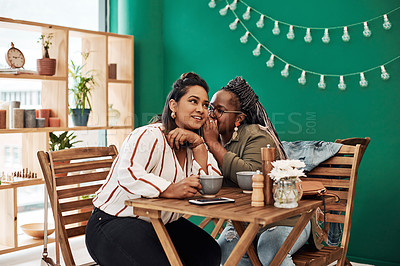 Buy stock photo Shot of two young women gossiping at a cafe