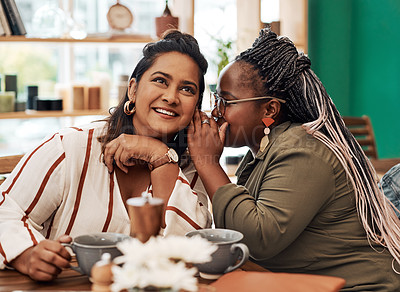 Buy stock photo Shot of two young women gossiping at a cafe