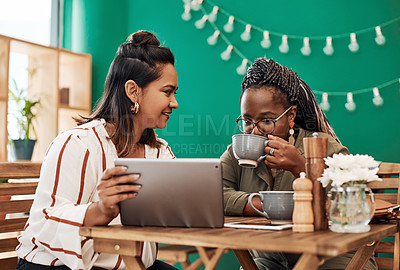 Buy stock photo Shot of two young women using a digital tablet together at a cafe