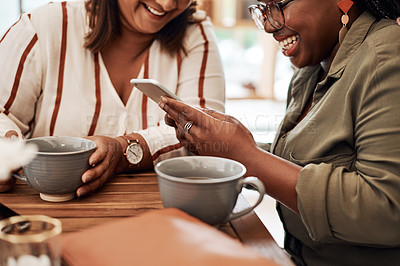 Buy stock photo Cropped shot of two women using a smartphone together at a cafe