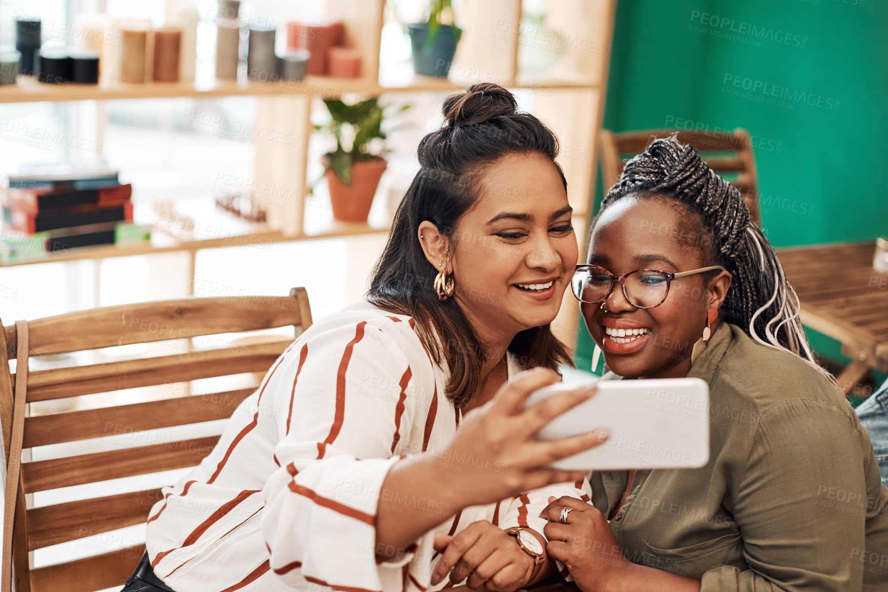 Buy stock photo Shot of two young women taking selfies at cafe