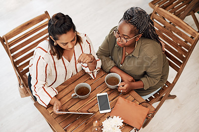 Buy stock photo High angle shot of two young women using a digital tablet together at a cafe