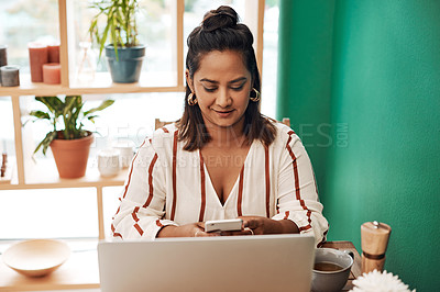 Buy stock photo Shot of a young woman using a smartphone and laptop at a cafe