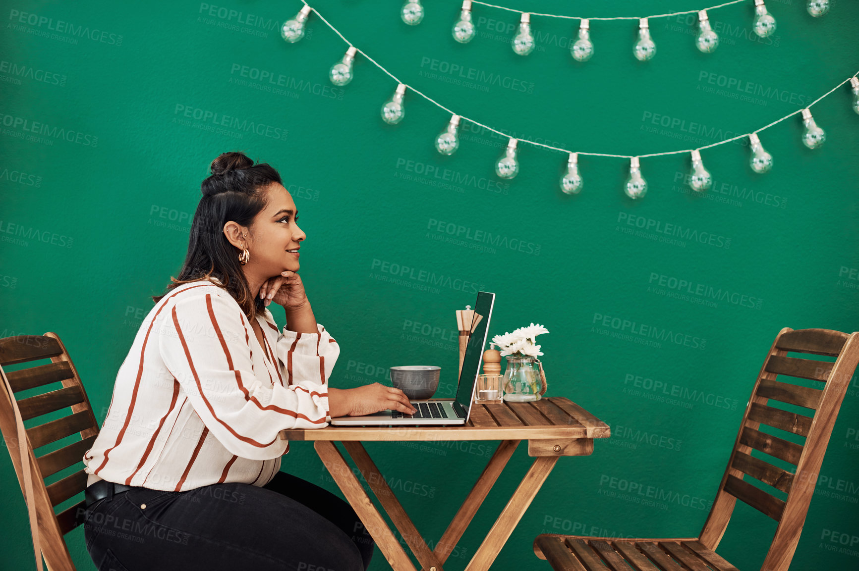 Buy stock photo Shot of a young woman looking thoughtful while using a laptop at a cafe