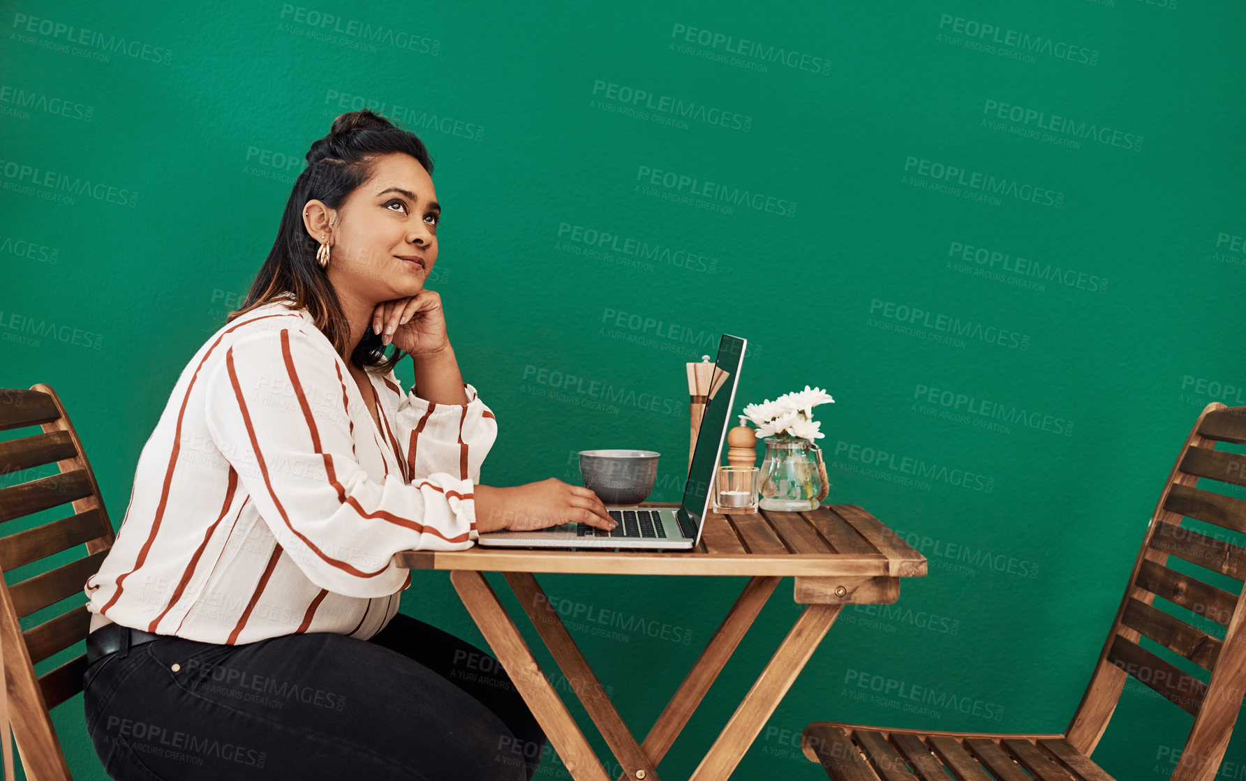 Buy stock photo Shot of a young woman looking thoughtful while using a laptop at a cafe