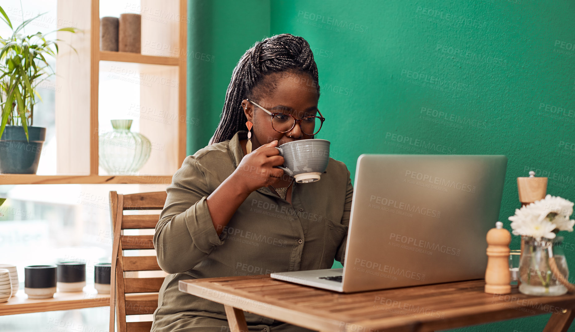 Buy stock photo Shot of a young woman having coffee and using a laptop at a cafe