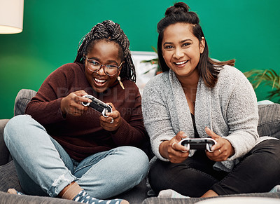Buy stock photo Shot of two young women playing video games on the sofa at home