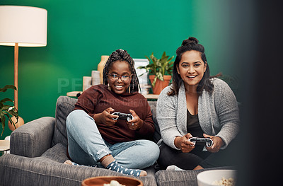 Buy stock photo Shot of two young women playing video games on the sofa at home