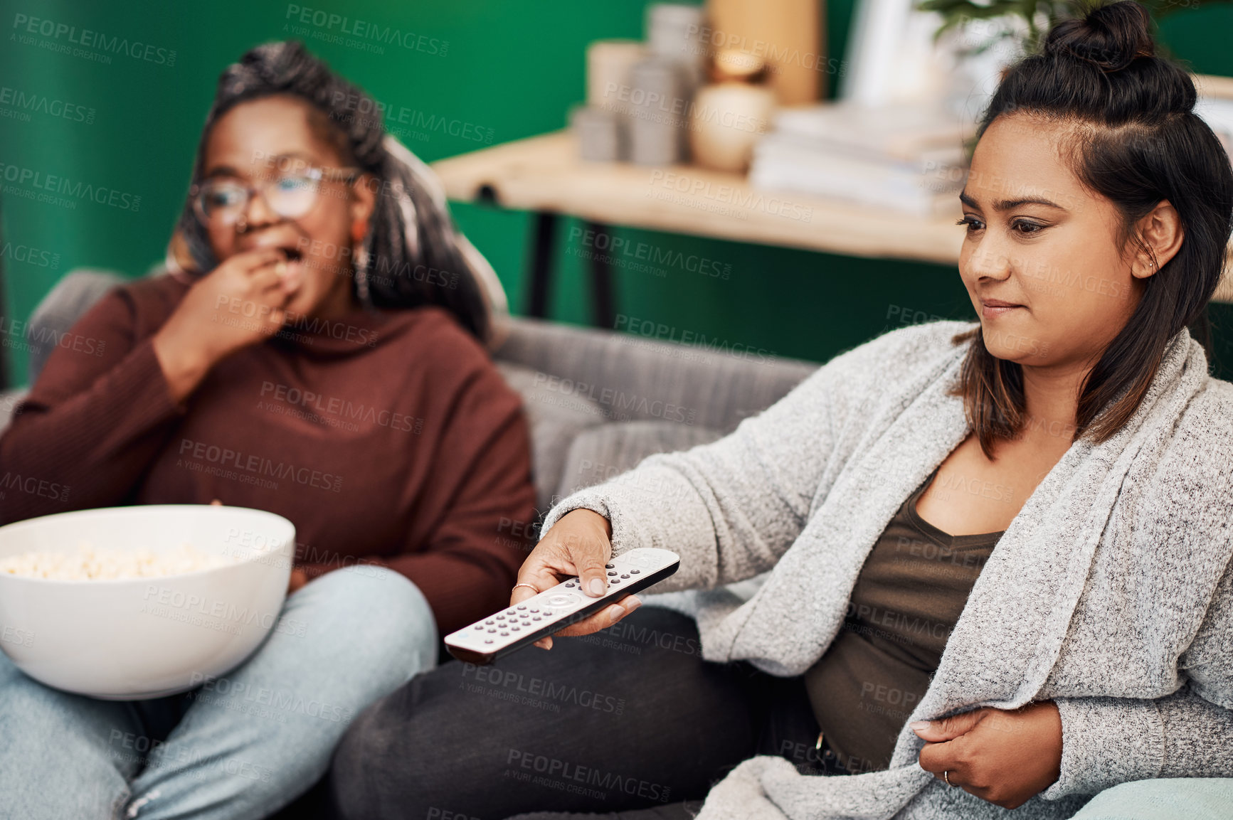 Buy stock photo Girl friends, watching tv and remote in home living room on a couch with snack eating. Series, movie and women together in a lounge with a female friend looking at a television in house with popcorn