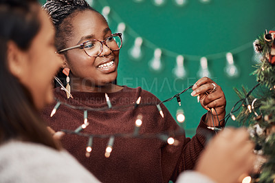 Buy stock photo Shot of two young women decorating a Christmas tree at home