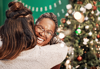 Buy stock photo Shot of two happy young women hugging each other during Christmas at home