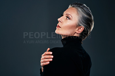 Buy stock photo Studio shot of a beautiful mature woman posing against a dark background
