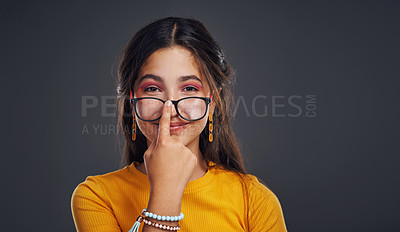 Buy stock photo Cropped portrait of an attractive teenage girl wearing glasses and standing against a dark background in the studio alone