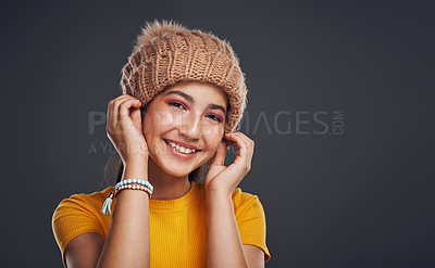Buy stock photo Cropped portrait of an attractive teenage girl wearing a beanie and standing against a dark background in the studio alone