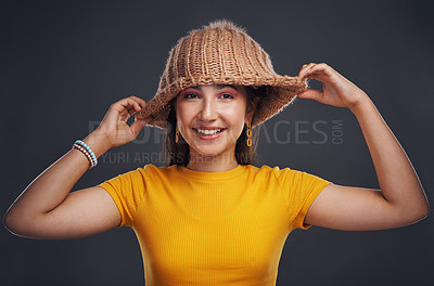 Buy stock photo Cropped portrait of an attractive teenage girl wearing a beanie and feeling playful against a dark studio background