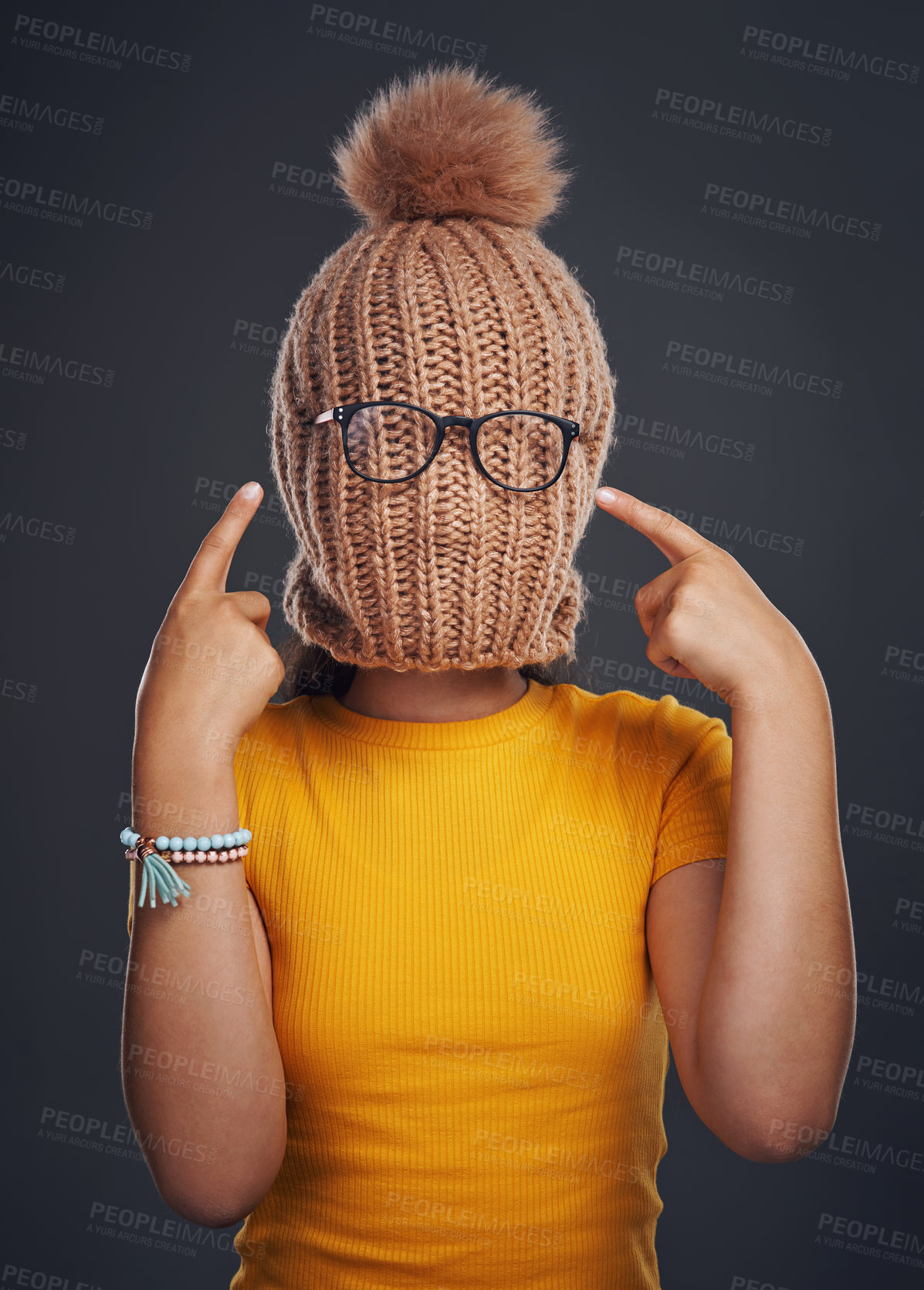 Buy stock photo Fashion, hide and girl with beanie in studio pointing with glasses for funny, comic or silly joke. Goofy, style and woman cover face with knit hat and spectacles for comedy by black background.