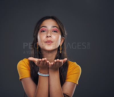 Buy stock photo Cropped portrait of an attractive teenage girl standing alone and blowing kisses against a dark studio background