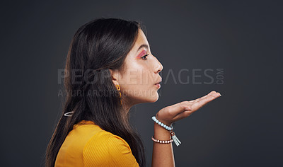 Buy stock photo Cropped shot of an attractive teenage girl standing alone and blowing kisses against a dark studio background