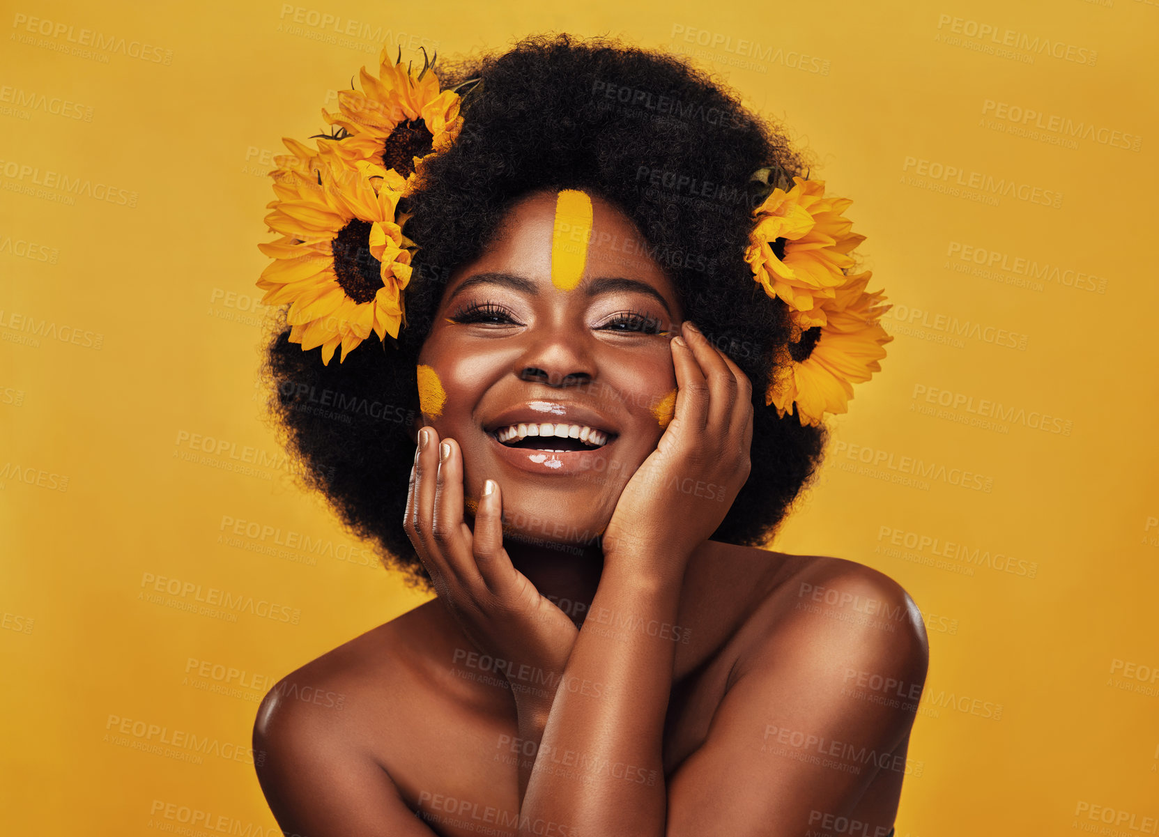 Buy stock photo Studio portrait of a beautiful young woman smiling while posing with sunflowers in her hair against a mustard background